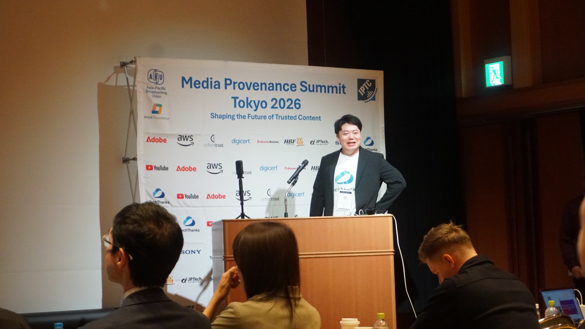 Media Provenance Summit Tokyo 2026 のバックボードの前でライトニングトークを行う弊社代表